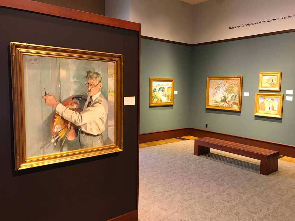 Image of a gallery interior with paintings hanging on the walls.